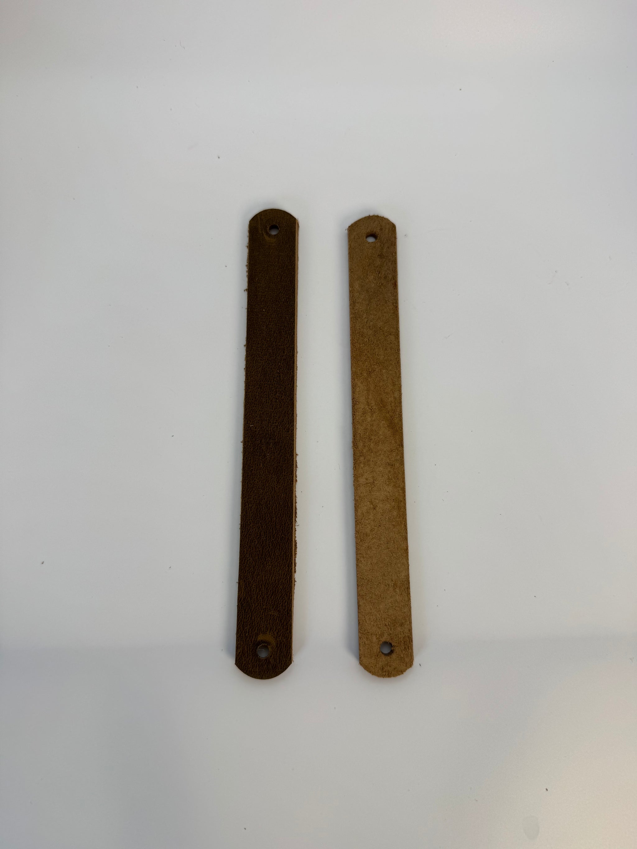 Two bronze-colored metal strips on a white background